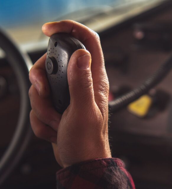 Image of a hand holding a CB radio inside of a truck